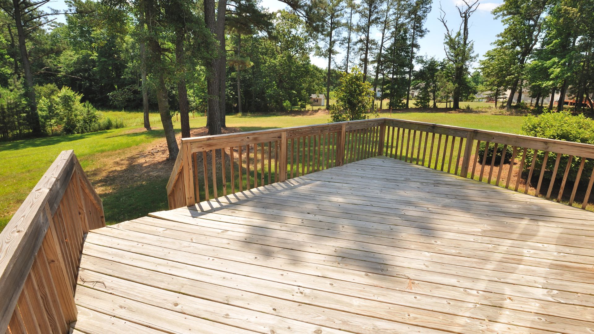 A wooden deck with railings and trees in the background