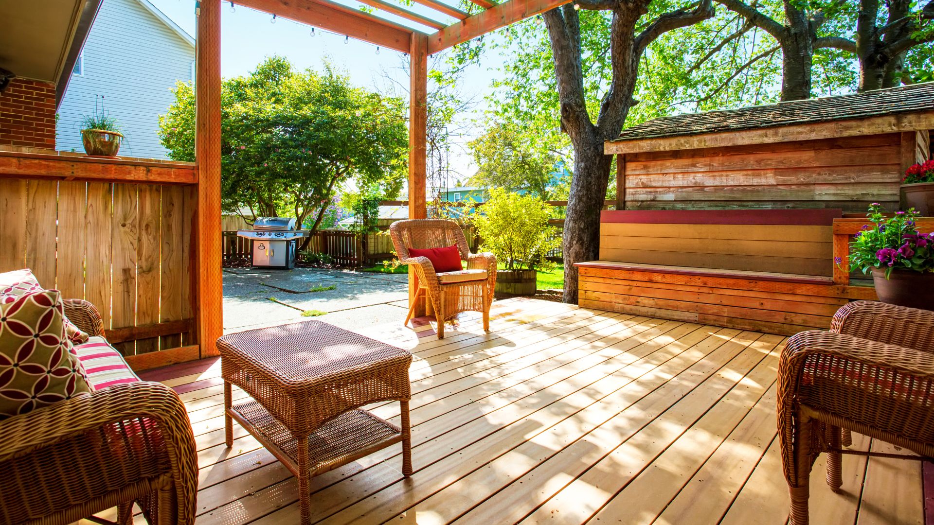 A wooden deck with wicker chairs and a table