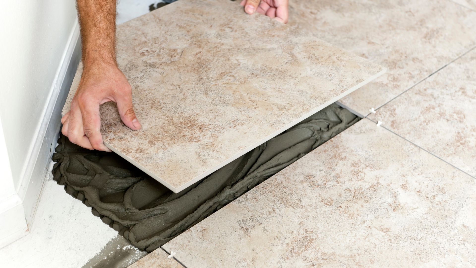 A man laying tile on the floor of a bathroom